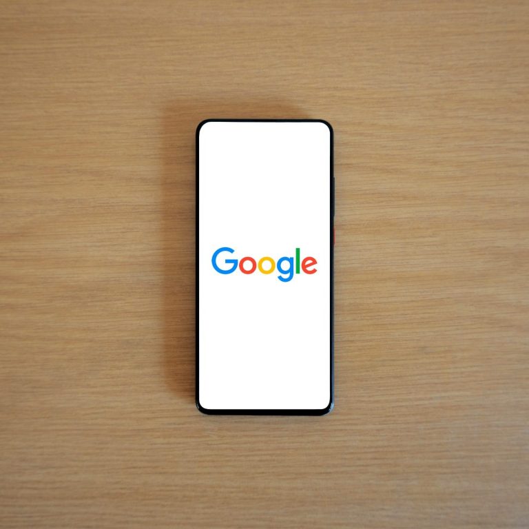 Ein Smartphone mit dem Google-Logo auf einem Holztisch.