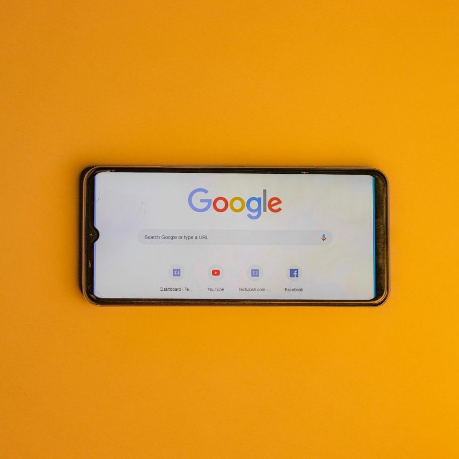 Smartphone mit Google-Suchleiste auf orangefarbener Hintergrund.